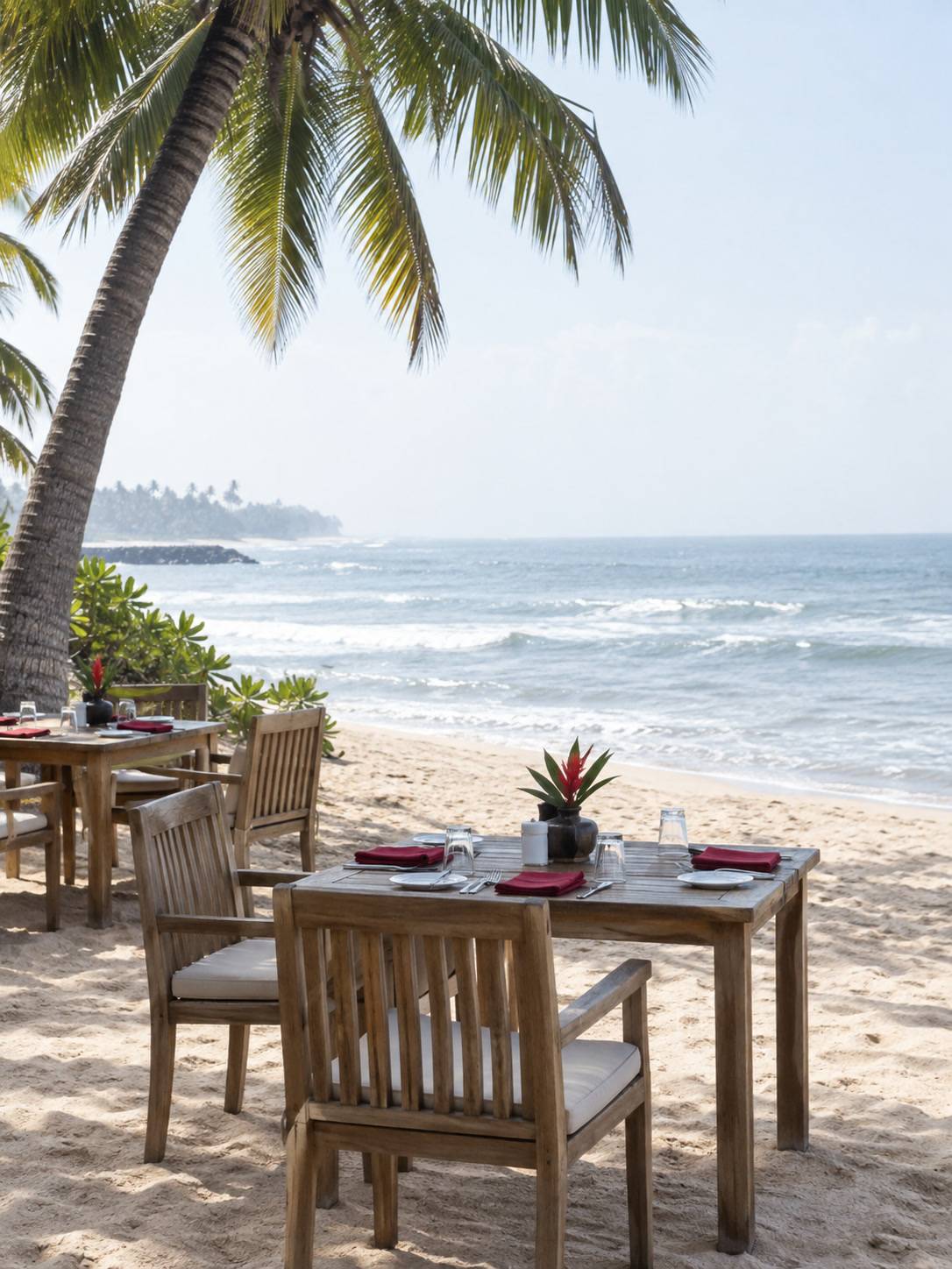 Outdoor restaurant tables on pale sand, Waskaduwa sea behind, late-morning light